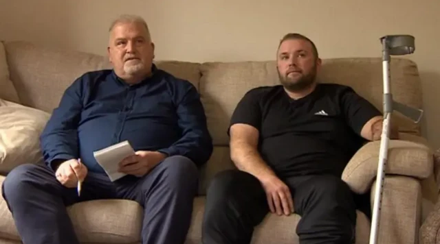 Two men on a sofa looking to the side