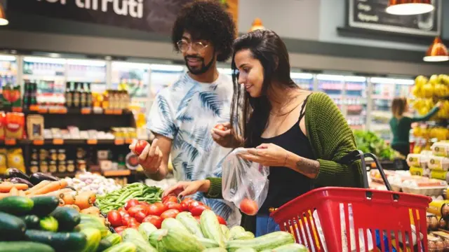 Casal escolhe tomates na seção de hortifruti do supermercado