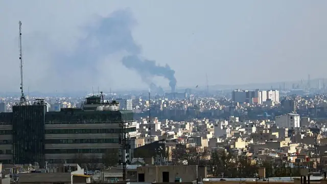 در تصویر، ستون‌هایی از دود خاکستری‌رنگ از محل یک حمله در تهران در اول آوریل ۲۰۲۶ به آسمان بلند شده است. دود غلیظ بخش بزرگی از پس‌زمینه را پوشانده. این صحنه از فاصله‌ای دور ثبت شده و ساختمان‌ها و سازه‌های شهری در پایین تصویر دیده می‌شوند. تهران، اول آوریل ۲۰۲۶