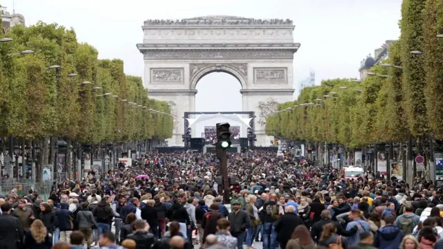 People waka down di Champs Elysees avenue during di 'car free' day for Paris on October 1, 2017.