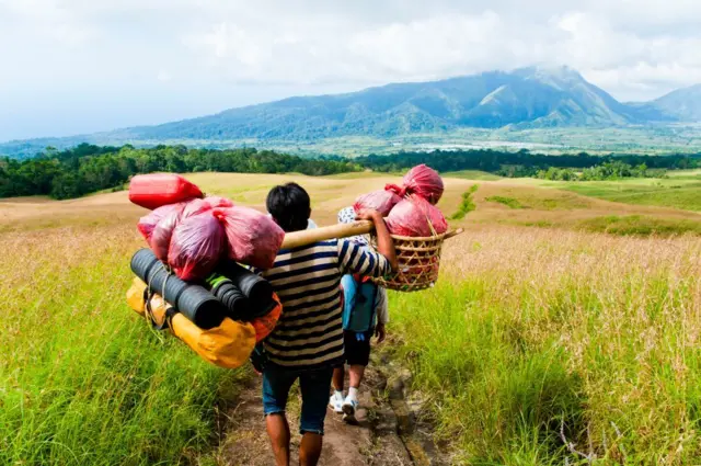 Seorang porter membawa barang-barang pendaki di Gunung Rinjani.