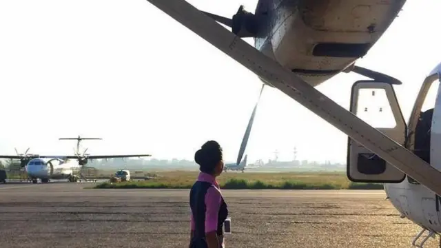 नेपाल वायुसेवा निगमकी एक परिचारिका एउटा विमान नजिकै उभिएको अवस्थामा