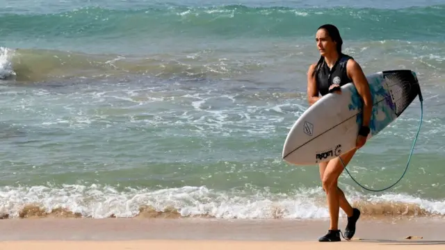 Un touriste marche après avoir surfé sur la plage de Mirissa, dans le sud du Sri Lanka