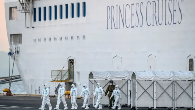 Personal sanitario desciende de un barco en cuarentena.