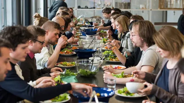 Grupo de personas sentadas comiendo vegetales.