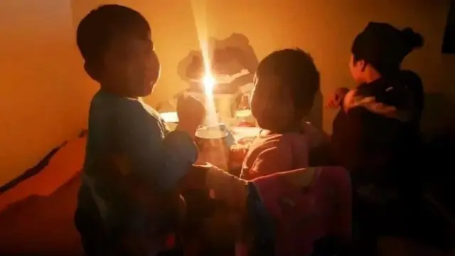 Электр йўқлигидан шам ёруғида ўтирган болалар