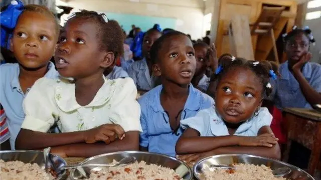Des enfants assis devant des plats.