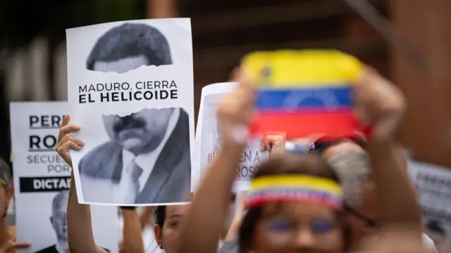 Foto de pessoas segurando cartazes em protesto contra a prisão de pessoas contrárias ao regime de Nicolás Maduro na Venezuela. 