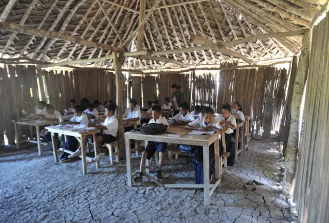 Siswa SMP Negeri 1 Kupang belajar di gedung sekolah seadanya dengan lantai tanah dan atap jerami serta fasilitas yang sangat minim di Sekolah Menengah Pertama Negeri 1 Kupang, Nusa Tenggara Timur (NTT), Indonesia, pada 08 Mei 2018. Sejak tiga tahun lalu, sejak sekolah tersebut dibangun secara swadaya masyarakat hingga kini belum memiliki fasilitas bangunan yang memadai dan layak, sehingga pada musim panas para siswa dan guru harus belajar di tengah debu dan lumpur saat musim hujan, sedangkan sekolah jarak jauh dengan Pemerintah Kota Kupang, Provinsi Nusa Tenggara Timur sebanyak 5.000 ruang kelas sekolah di NTT rusak dan tidak terbangun.