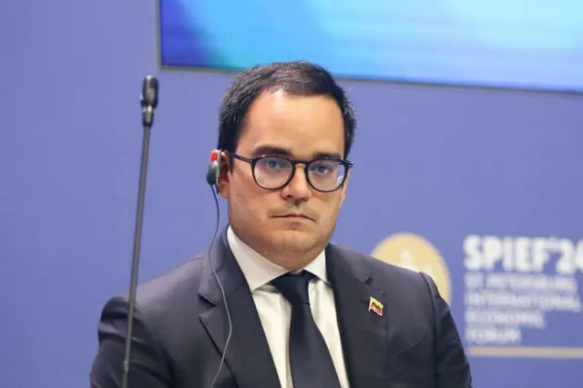 Calixto Ortega Sánchez, vestido con traje y corbata y un pin con la bandera de Venezuela en la solapa, con un audífono en el oído de los que suelen usarse en las conferencias para traducción simultánea.