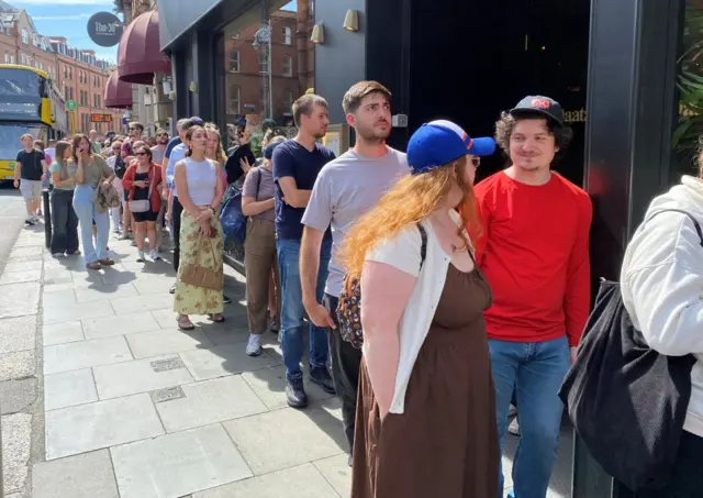 Pessoas fazem fila na George's Street, em Dublin, na Irlanda, para comprar óculos especiais para observar o eclipse solar.