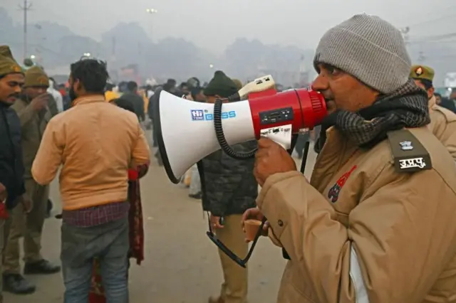 गङ्गा, यमुना र गुप्त सरस्वती नदीको त्रिवेणीमा स्नान गर्न जान लागेका तीर्थयात्रीलाई निर्देशन दिँदै एक प्रहरी अधिकारी 
