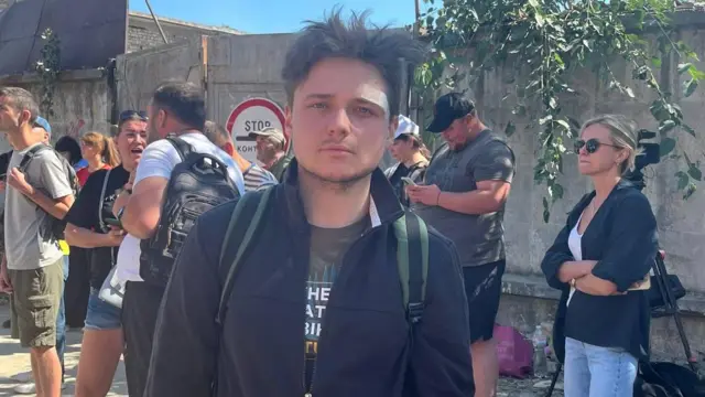 Андрій, над лівим оком у нього пластир, на задньому тлі стоять люди