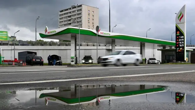 Заправка компании «Татнефть» в московском спальном районе отражается в луже 