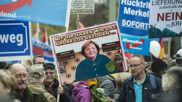 Almanya'da AfD partisinin gösterisinde Merkel'i, eski sosyalist hareketi Özgür Sosyalist Gençler üniformasıyla resmedilen pankartlar taşındı.