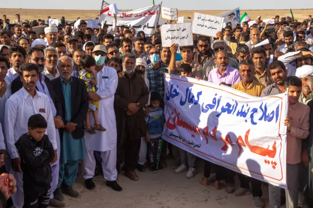 شاوخوا ۵۰ کسان د ۲۰۲۵ کال د اپریل په ۲۳مه د وچ شوي هامون جهيل په بستر کې، چې په ایران کې دریم لوی او ترټولو تازه د اوبو جهيل دی، یوځای سره ولاړ دي او بینرونه یا دړې یې په لاس کې دي. 