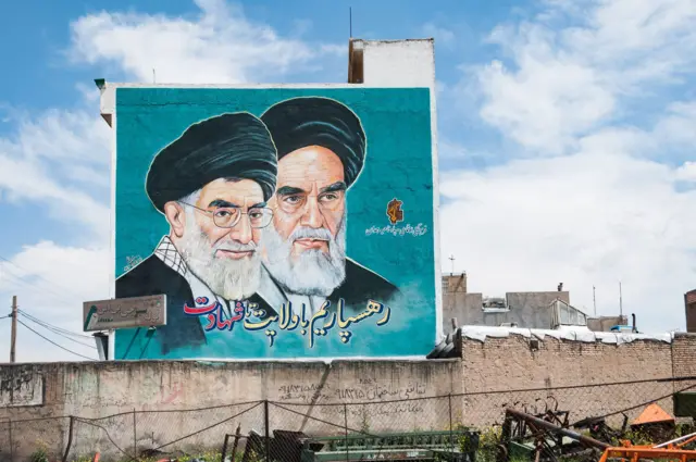 Esta imagem foi tirada em Hamadan, no oeste do Irã, em abril de 2013. O mural representa o primeiro e o segundo líderes supremos do Irã. O aiatolá Khomeini (à direita) foi o primeiro líder supremo após a Revolução Islâmica. O aiatolá Ali Khamenei (à esquerda) foi seu sucessor desde 1989.
