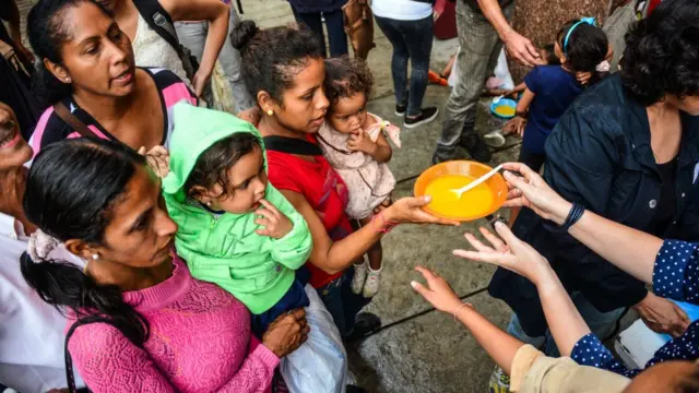 Personas esperan plato de comida en Caracas