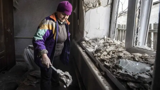 Mulher limpa a casa danificada após ataqueartilhariauma áreaDonetsk, sob o controlerebeldes apoiados pela Rússia,23fevereiro