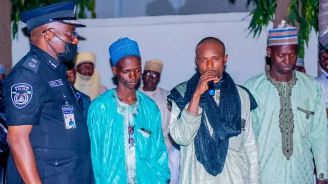 Un policier se tient aux côtés de trois hommes accusés d'avoir kidnappé des étudiants