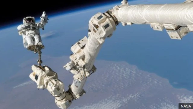 การออกเดินในอวกาศ (Spacewalk)โดยยึดตัวเองไว้กับแขนกลซึ่งเป็นส่วนหนึ่งของสถานีอวกาศ