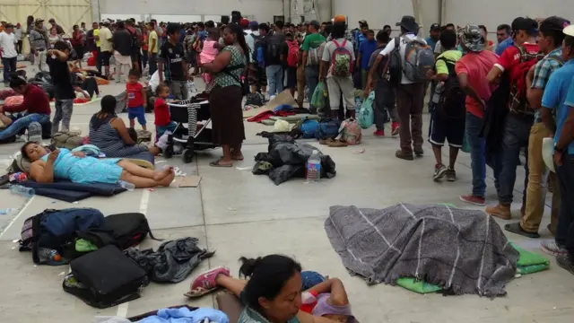 Migrantes descansan en un auditorio