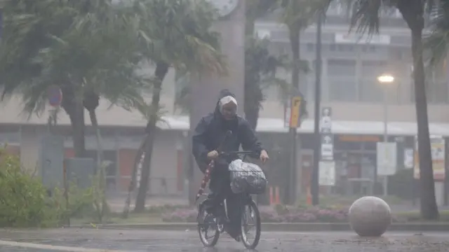 Um homem pedalaeliminatórias da copa do mundo fifa de 2024 uefameio a chuva torrencial e ventos na cidadeeliminatórias da copa do mundo fifa de 2024 uefaMiyazaki depois que o tufão Nanmadol atingiu o Japão