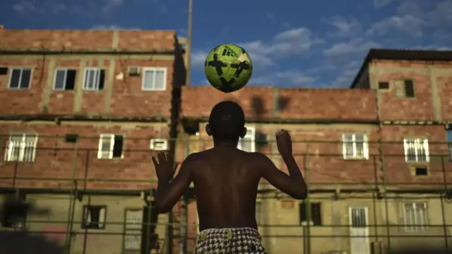 Un niño juega con un balón en una favela de Brasil.