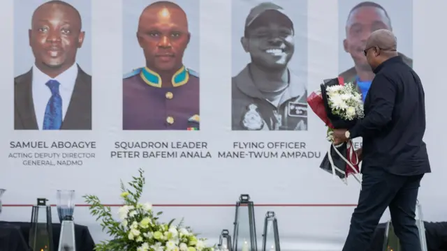 Ghana's president carries a flower bouquet to pay respect to the victims at the ceremonial garden at the seat of government. 
