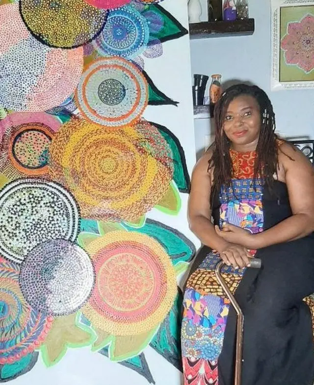 Ijeoma Ogwuegbu à côté d'une grande peinture Dot Art
