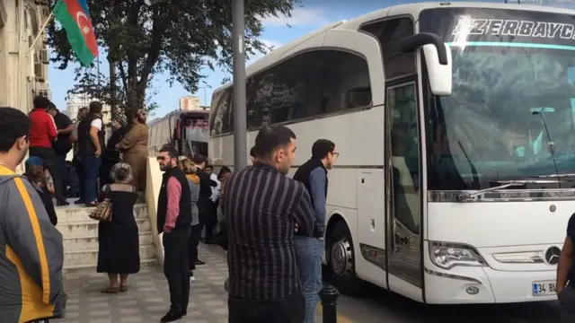 Белый автобус и провожающие родственники.