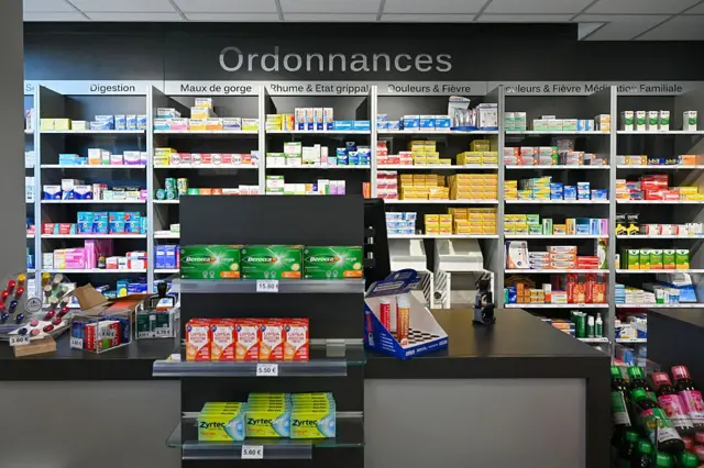 Sebuah toko obat tanpa ada orang, hanya beberapa etalase terbuka yang menempel di tembok berisi obat-obatan.