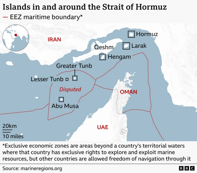 A map of di Strait of Hormuz showing di surrounding coasts of Iran to di north and Oman and di UAE to di south. Several islands in di strait dey labelled, including Hormuz, Larak, Qeshm, and Hengam near Iran, and Greater Tunb, Lesser Tunb, and Abu Musa further southwest. Red lines mark exclusive economic zone (EEZ) maritime boundaries. Di area around Greater Tunb, Lesser Tunb and Abu Musa dey labelled “Disputed.” A footnote explain dat EEZs give countries exclusive rights to marine resources while allowing freedom of navigation. 