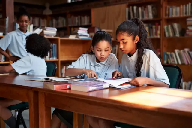 Dos niñas ven un libro en una biblioteca