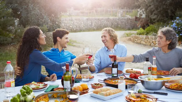 Rodziny siedzi przy zastawionym stole w ogrodzie podczas zachodu słońca