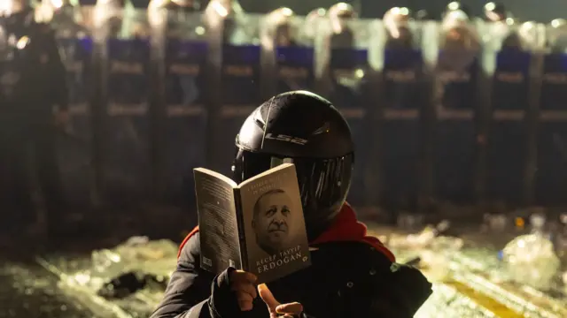 Seorang pengunjuk rasa membaca buku Erdogan di depan barikade polisi antihuru-hara saat para demonstran mencoba berbaris menuju Lapangan Taksim