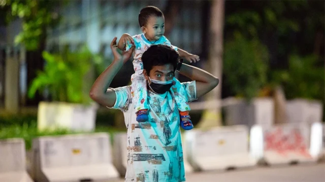 Un hombre asiático lleva sobre sus hombros a un pequeño