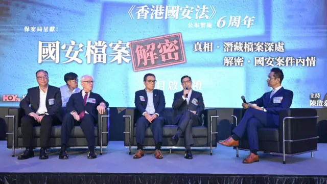 2026年6月29日,香港保安局就電視節目《國安檔案解密》舉行啟播禮。圖中人士包括保安局局長鄧炳強、懲教署懲教事務監督林賜良、法學教授江樂士資深大律師、香港警務處國家安全處總警司李桂華、節目主持人陳啟泰。