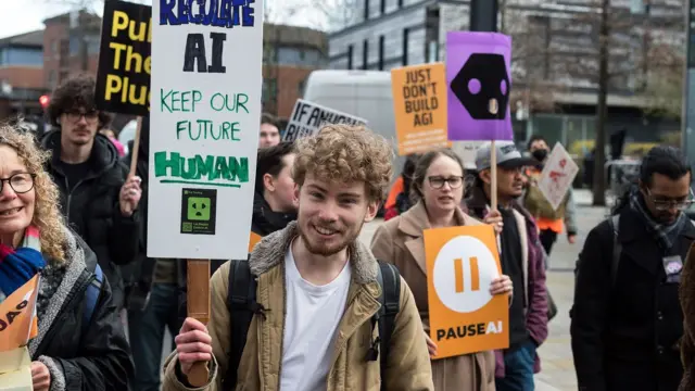 Yapay zeka karşıtı bir gösteride pankartlar taşıyan gençler. 