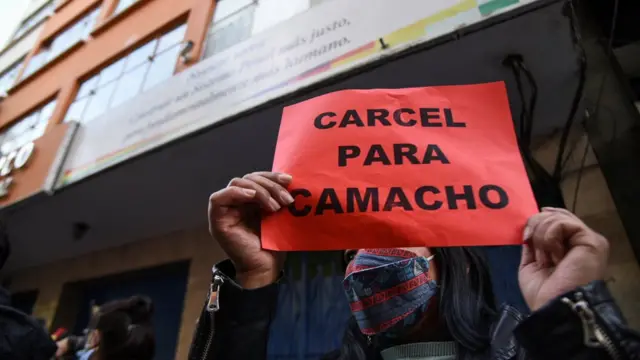 Una mujer con un cartel que dice "Cárcel para Camacho"