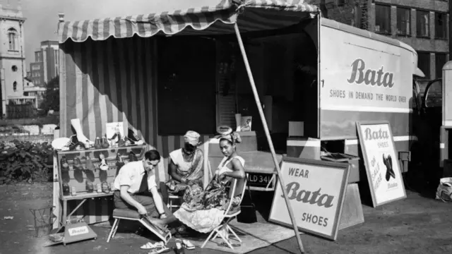 Penjual sepatu Colin Richards mengukur kaki seorang wanita muda di demonstrasi toko sepatu kelilingnya yang menjual sepatu Bata, sebelum berangkat ke Afrika dalam acara penjualan, London, September 1951