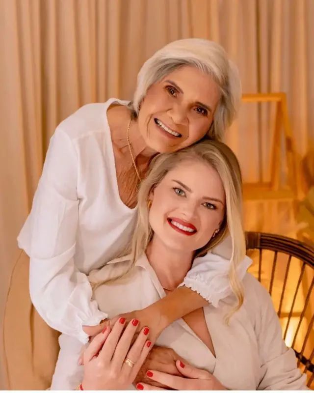 Mãe e filha abraçadas em retrato profissional usam roupas brancas