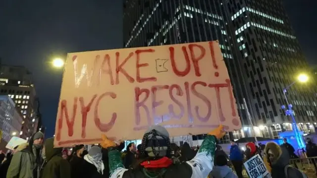 Демонстранты в Нью-Йорке вечером держат большой плакат с надписью "Проснитесь! Нью-Йорк, сопротивляйся!"