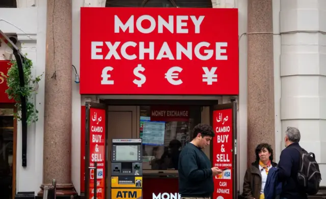 Des personnes se tiennent devant un bureau de change à Londres, en Angleterre. 