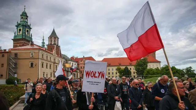 Люди идут с флагами Польши, на транспаранте на переднем плане написано Wołyń, буквы написаны красным и с них стекает кровь