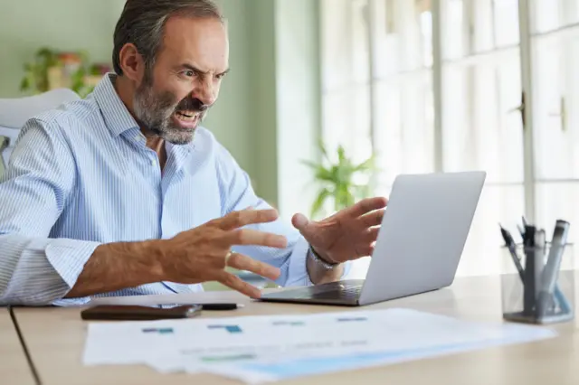 Empresário irritado discute com alguém durante uma videoconferência no escritório