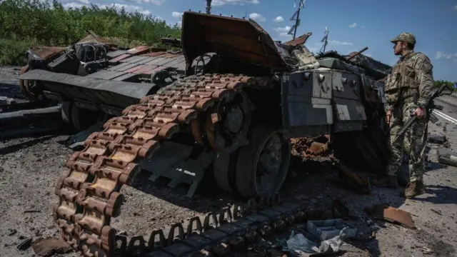 Um soldado ucraniano olha para um tanque ucraniano destruído perto da vilaagen288 slotRobotyne