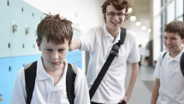 Menino segurando a cabeçapixbet gcolegapixbet gvestiário na escola