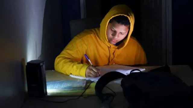 Ismail Sha étudie à l'aide d'une lanterne rechargeable pour son examen final pendant l'une des fréquentes coupures de courant, appelées délestages, de la compagnie d'électricité sud-africaine Eskom, en raison du vieillissement des centrales à charbon, au Cap, en Afrique du Sud, le 25 octobre 2022.