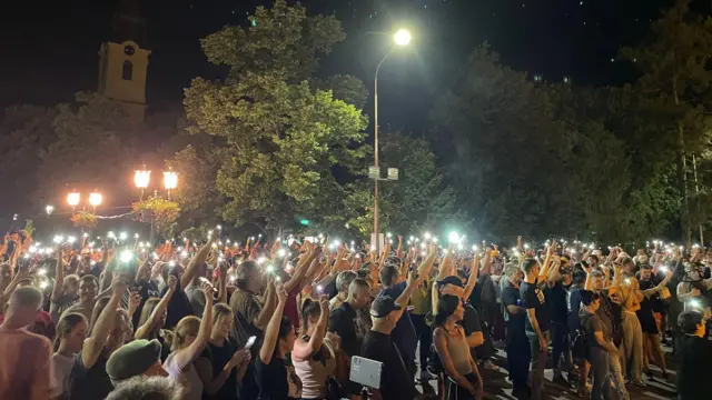 Људи држе светла телефона у мраку